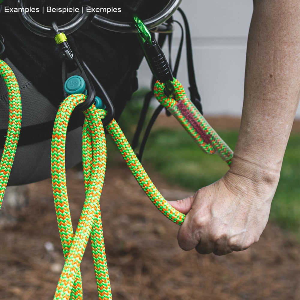 Sidekick product in black with two turquoise buttons, attached to a climbing harness with green and orange climbing line, hand holding an orange climbing line