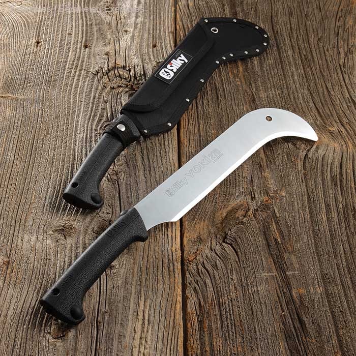 Yoki Machete 270 by Silky with black handle and silver blade, lying on wooden background next to black sheath with Silky logo
