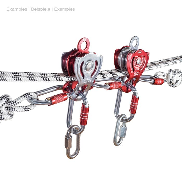 Two Janus Pro pulley blocks from CAMP made of metal in silver and red, each attached to a rope, with carabiners and knots on the ropes