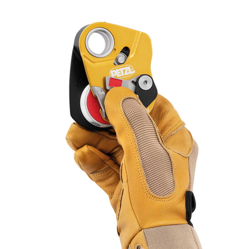 Petzl Mini Traxion Pulley in Yellow and Black is held by one hand with a yellow work glove