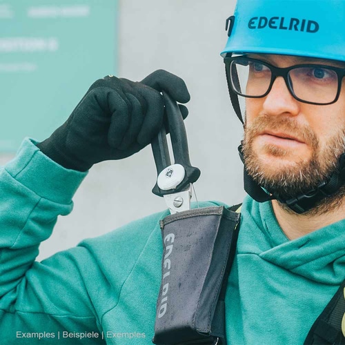 Man in blue Edelrid safety helmet and green jacket holding black scissors from Edelrid's black Edelrid Rescue Holster
