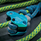 Flexbee close-up of blue belay device with blue and yellow climbing rope on black background