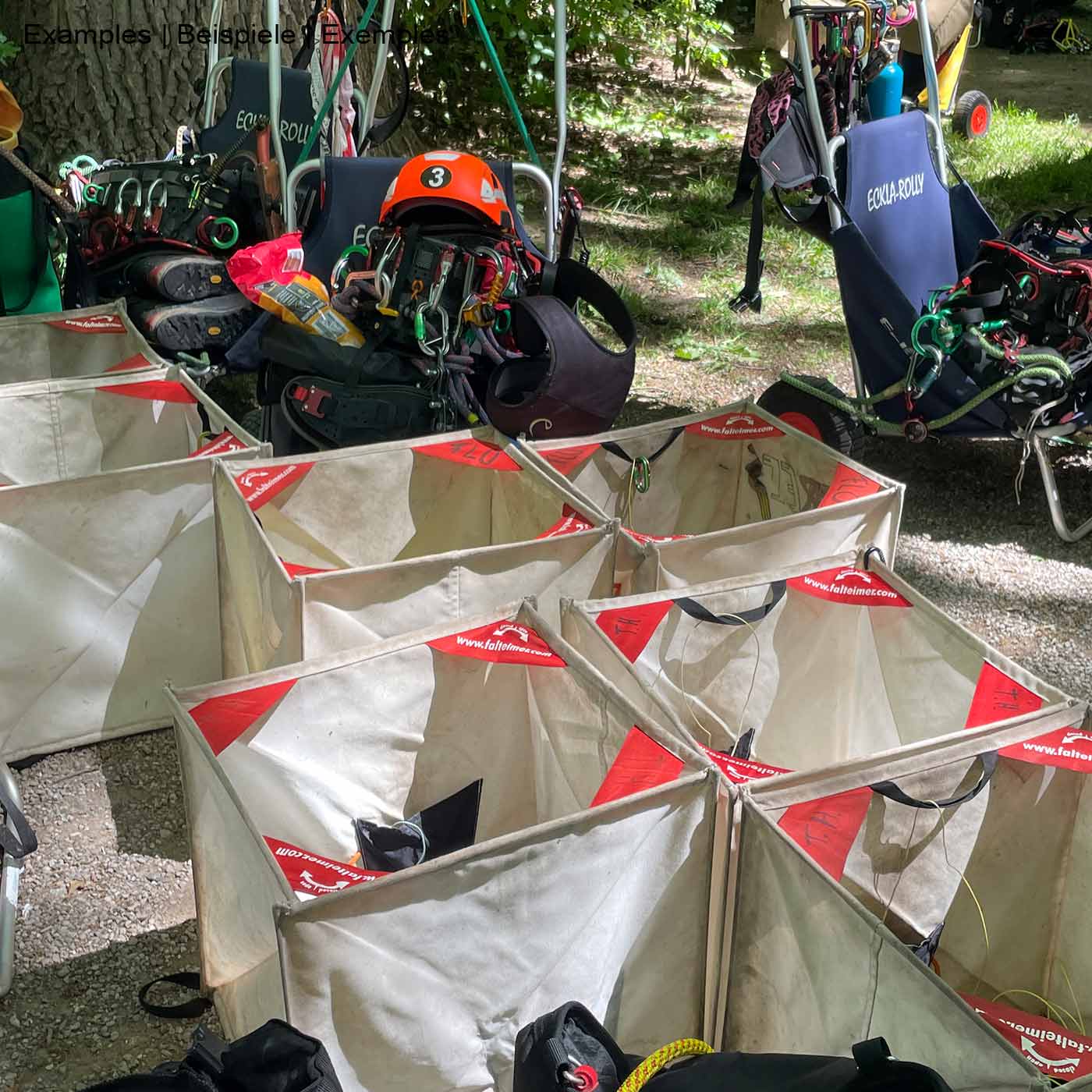 Folding bucket SINGLE, several white foldable buckets with red corners standing outdoors, in the background climbing equipment